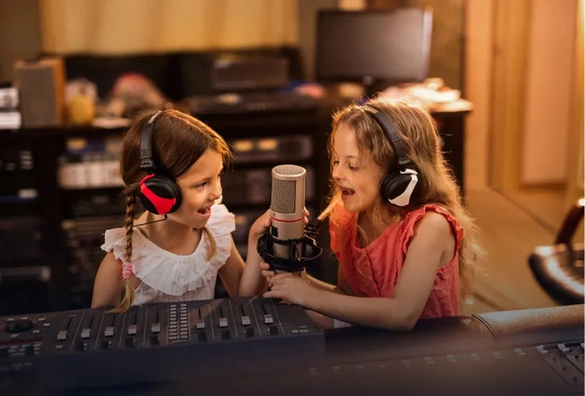 Two girls wearing headphones recording a podcast at a studio mixing desk, developing hosting and communication skills
